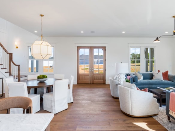 A spacious living room with large windows, white walls, and contemporary furniture.