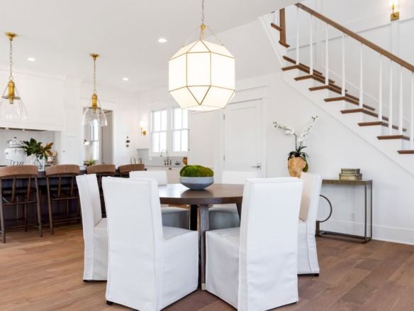 Bright, spacious dining area with white walls, wooden floors, and elegant lighting.