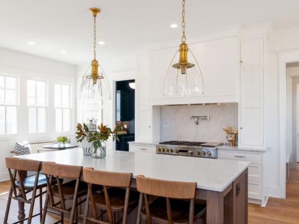 Bright white kitchen with island, pendant lights, and natural sunlight.