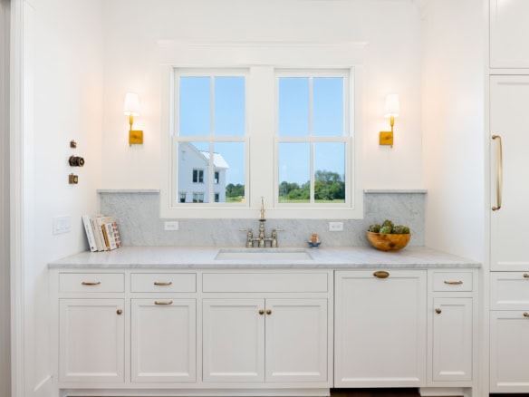 Bright white kitchen with large window and elegant cabinetry.