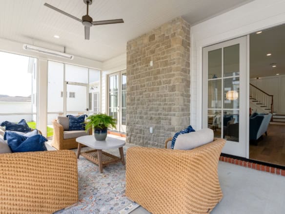 Sunroom with stone wall, wicker chairs, and large windows for natural light.