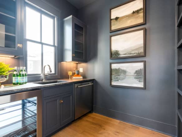 Contemporary kitchen featuring blue cabinets, large window, and lake scenery.