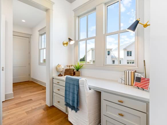 Bright home office with large windows, white desk, and natural light.