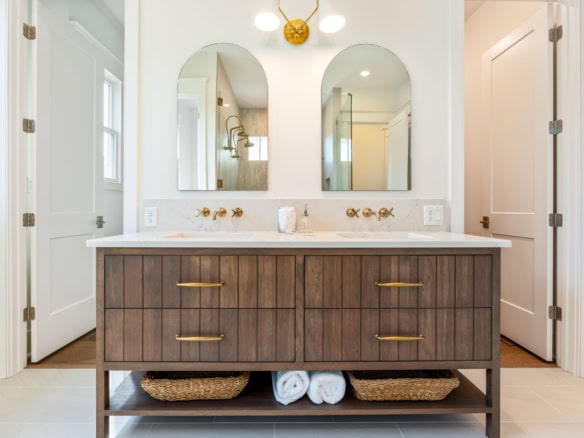 Modern bathroom vanity with double sinks, mirrors, and gold fixtures.