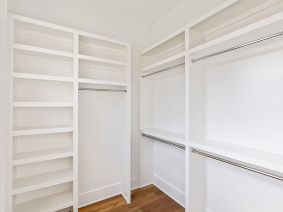 Bright white walk-in closet with multiple shelves and hanging rods.