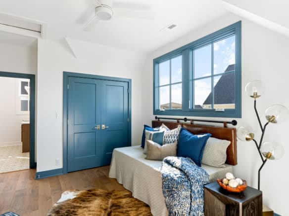 Bright bedroom featuring blue doors, large window, and cozy decor.