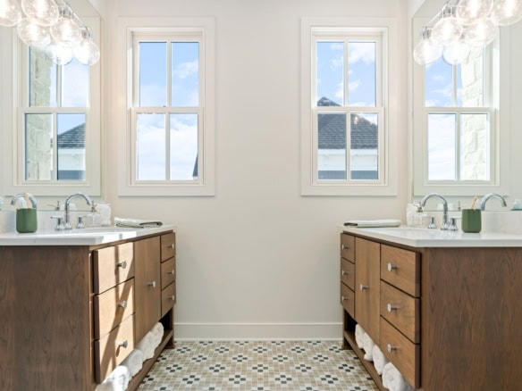 Bright bathroom featuring dual vanities, large windows, and elegant lighting.