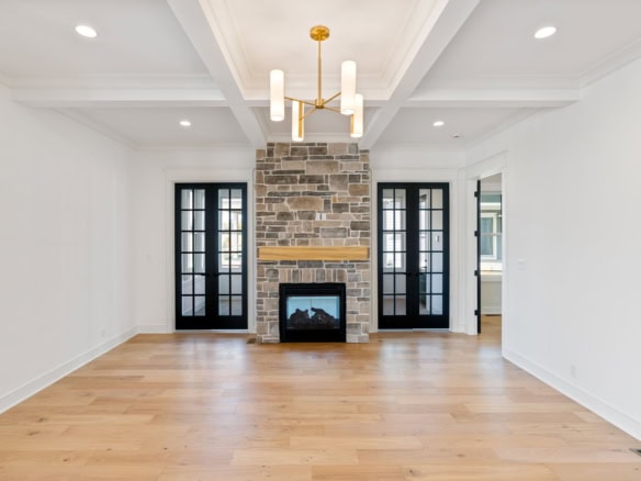 Bright living room with fireplace, stone accent wall, and double glass doors.
