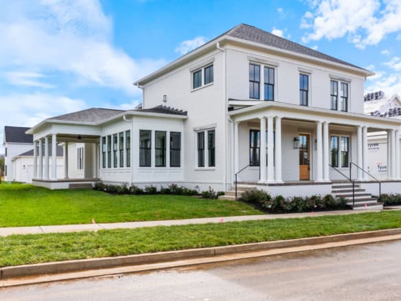 New white residential house with porch, windows, and landscaped yard.