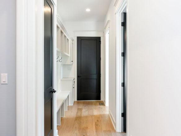 Bright, modern hallway with white walls, black door, and wooden flooring.