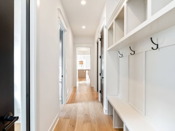 Bright hallway featuring built-in storage, hooks, and hardwood flooring.