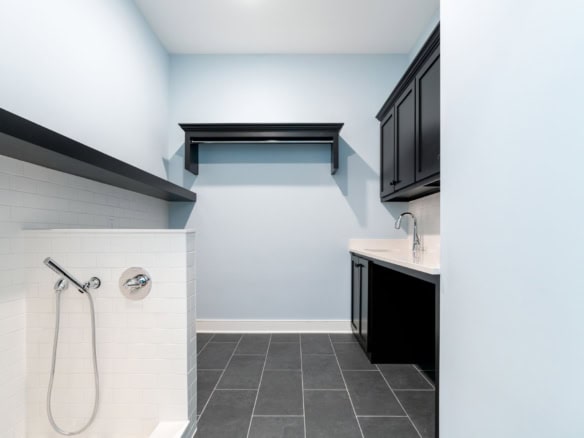 Modern laundry room with black cabinets and tiled floor.