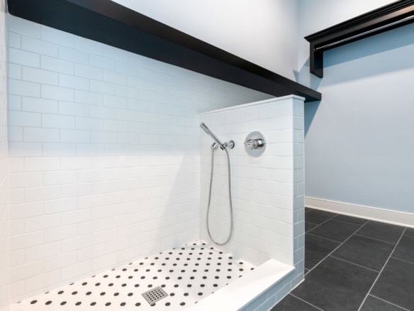 Modern walk-in shower with white tiles and black accents.