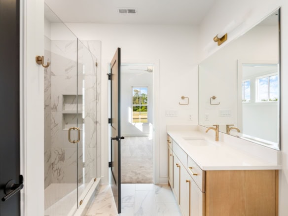 Bathroom with white walls, marble accents, and gold hardware.