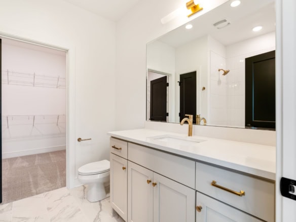 Bathroom interior with white cabinets, mirror, and gold hardware.