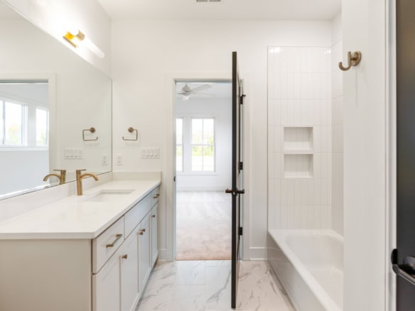 Bathroom with white vanity, bathtub, and built-in shower niche.