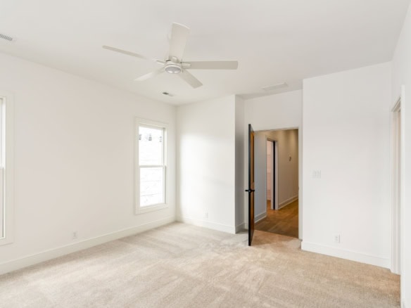 Bright, spacious room with white walls, windows, and ceiling fan.