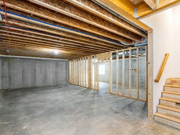 Interior view of a new basement under construction with framing and concrete floor.