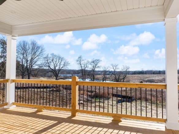 Deck overlooking scenic landscape with trees and open sky.
