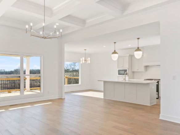 Spacious interior with large windows, white cabinetry, and contemporary lighting in a new home.