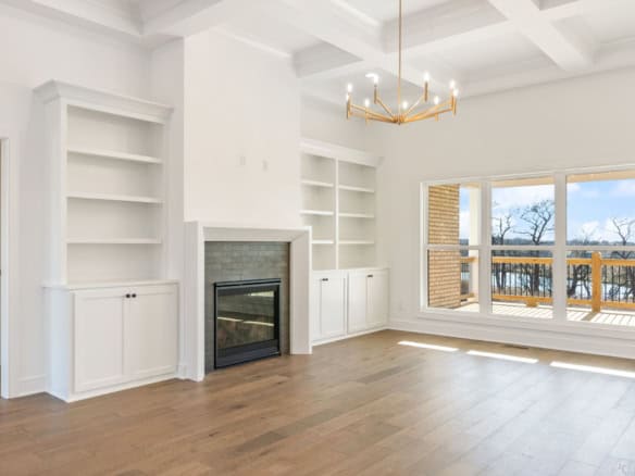 Spacious living room featuring a cozy fireplace, white built-in shelves, and large windows with a vi.