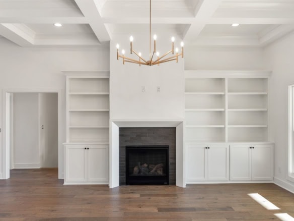 Interior view of a contemporary living room featuring a fireplace flanked by built-in white shelves.