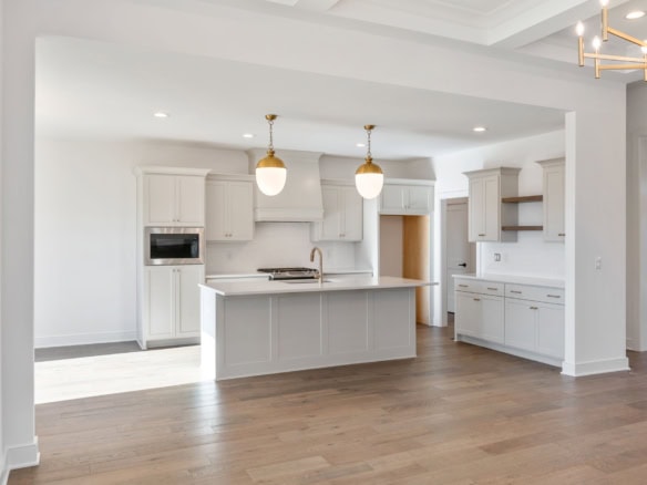 Modern kitchen with white cabinetry, island, and hardwood floors.