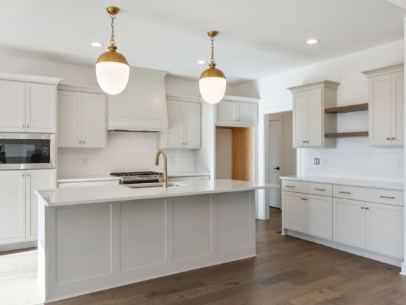 Elegant kitchen featuring white cabinets, gold pendant lights, and a spacious island.