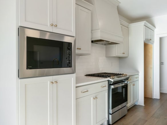 Modern white kitchen with stainless steel appliances and custom cabinetry.