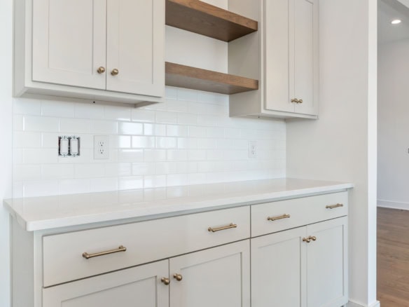 White kitchen cabinets with gold handles and open wooden shelves.