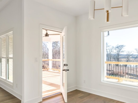 Interior view of a bright, spacious room with large windows and a balcony overlooking scenic landsca.
