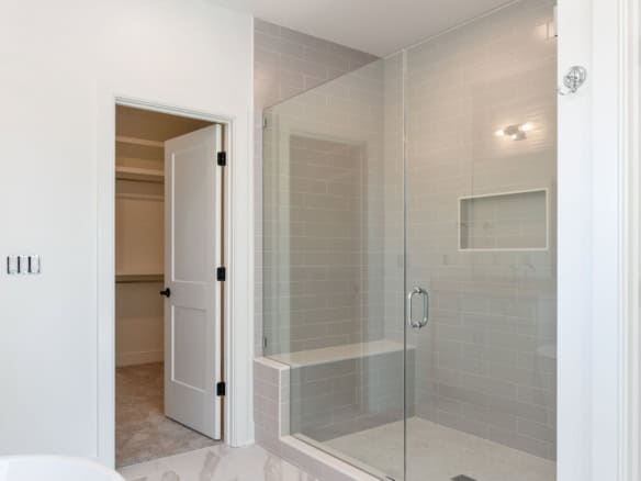 Bathroom shower with glass door and tiled walls.