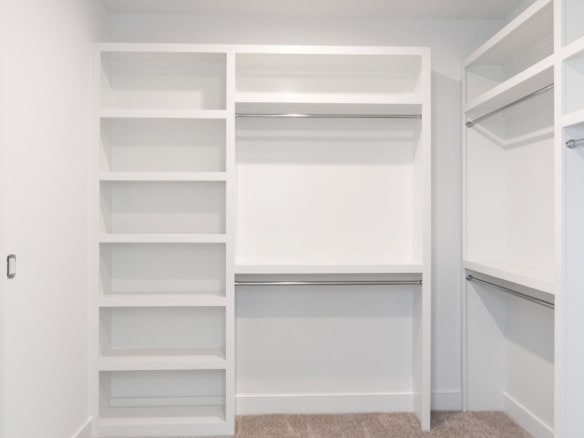 Custom white closet storage with shelves and hanging rods.