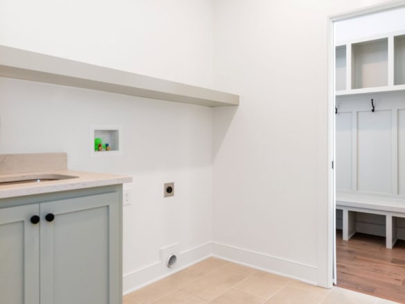 Laundry room with built-in cabinets and hooks for organization.