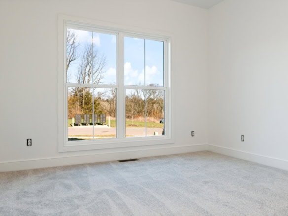 Bright empty room with large window overlooking a suburban street.