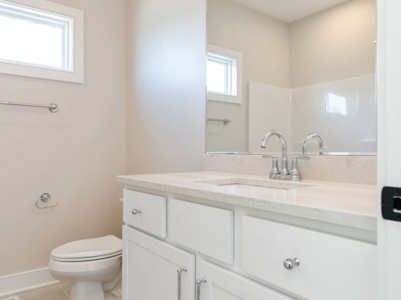 Bathroom with white vanity, marble countertop, and natural light.