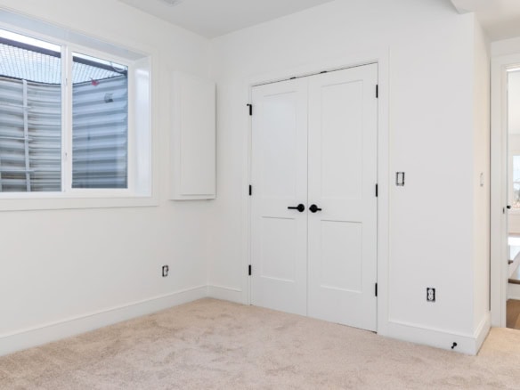 Interior room with white walls, double closet doors, and a window overlooking the backyard.