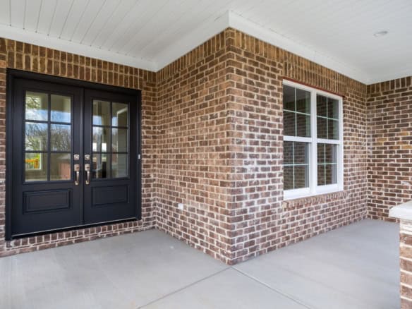 Modern brick exterior with black double doors and white-framed windows.