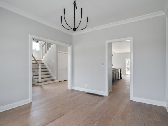 Interior view of a spacious, newly renovated home with light gray walls and hardwood flooring.