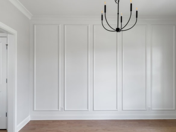 Elegant white wall paneling with a black chandelier in a new home.