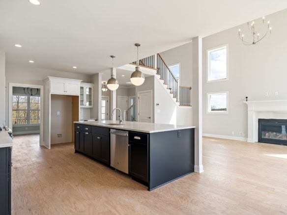 Spacious open-concept kitchen with black island and white cabinetry in a new home. Bright living spa.
