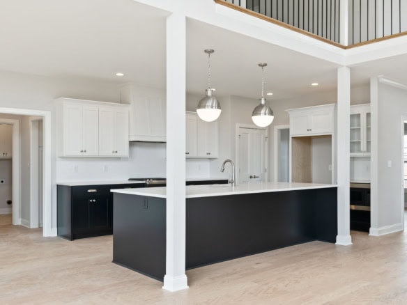 White kitchen with black island and pendant lighting.