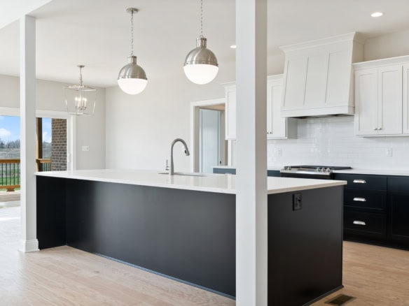 Bright, open-concept kitchen featuring a large island with a sleek black base and white countertop.
