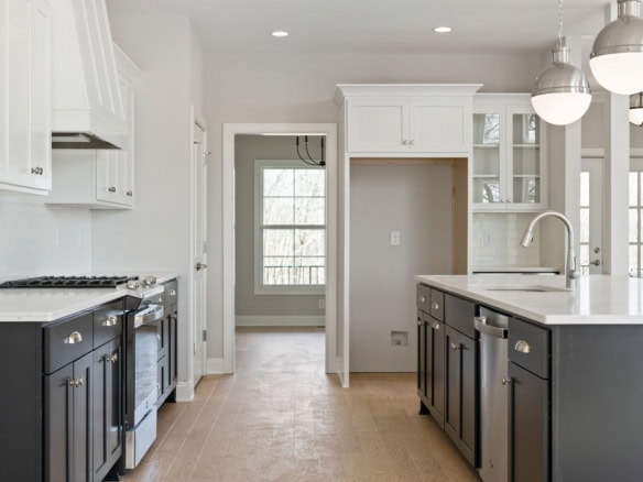 Modern kitchen featuring white cabinetry, a central island, and stainless steel appliances. Bright,.