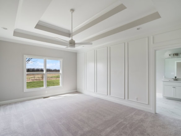 Spacious bedroom featuring a large window, white walls, and stylish ceiling details.