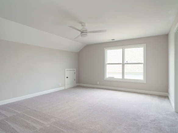 Bright, spacious interior room with large window and modern ceiling fan.