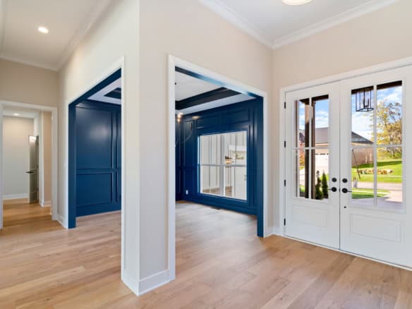Bright entryway featuring white walls and blue trim, leading to a spacious interior with natural lig.