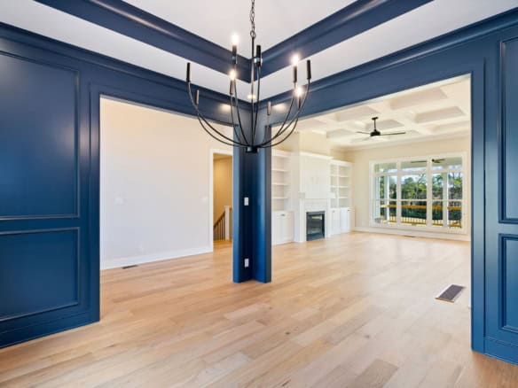 Bright living room with blue wall panels, hardwood floors, and large windows.