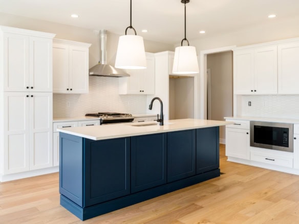 Modern kitchen with white cabinets and navy blue island.
