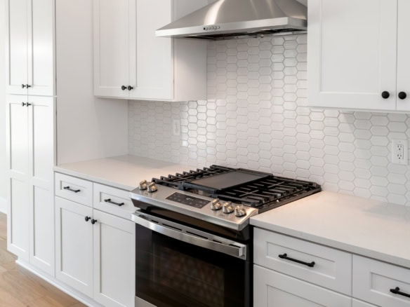 Elegant white kitchen with custom cabinets and a stylish backsplash.